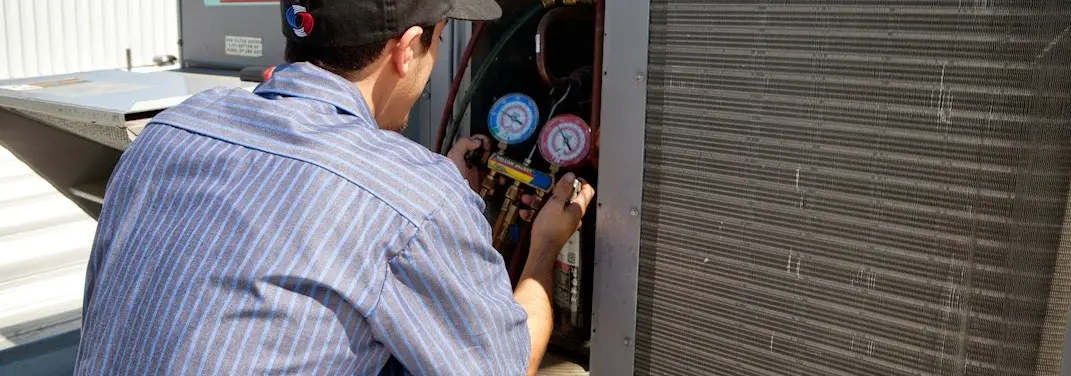 HVAC technician servicing a condenser unit in El Dorado