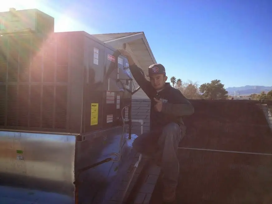 HVAC technician performing Air Duct Repair on a rooftop unit in El Dorado